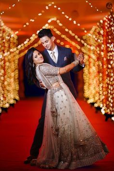 a man and woman are dancing on the red carpet with lights in the back ground