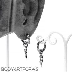 two pairs of earrings are hanging from the side of a white pole with text that reads body art forms