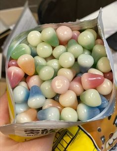 a person holding a box full of jelly beans in their hand with other candies