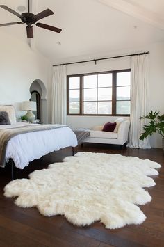 a bedroom with a bed, chair and rug on the floor in front of a window