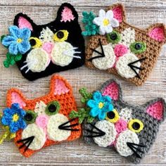 three crocheted cats with flowers on their heads are sitting next to each other