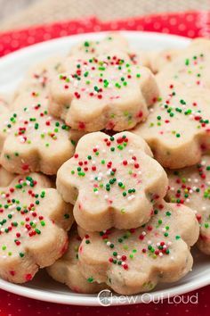 a white plate topped with cookies covered in sprinkles on top of a red table