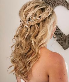 a woman with long blonde hair wearing a braided half up hairstyle in front of a heart shaped wall decoration