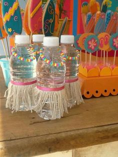 two plastic water bottles sitting on top of a wooden table next to candy pops and lollipops