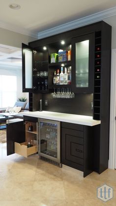 a modern home bar with built in wine cooler and liquor bottles on the wall behind it