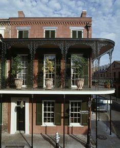 an old building with green shutters and flowers on the balconies in front