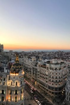 an aerial view of a city at dusk with cars and buildings in the foreground