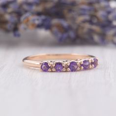 a close up of a ring with purple stones on it and lavender flowers in the background