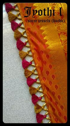 an orange and pink silk saree with tassels on the border, sitting on top of a white cloth