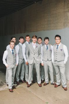 a group of young men standing next to each other in front of a cement wall