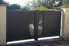 an iron gate with laser cut designs on it in front of a driveway and trees