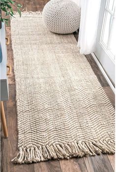 a white rug with fringes on the floor next to a window