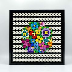 an art piece made out of colored paper with arrows and flowers in the center on a white background