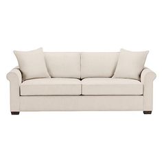 a white couch with two pillows on it's back and one arm facing the camera