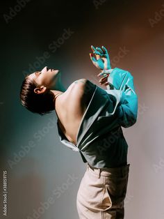 a woman with her hands up in the air while wearing a green shirt and khaki pants