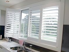 a kitchen with white cabinets and black counter tops is pictured in this image, the window blinds are closed