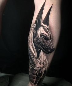 a man's leg with an egyptian style tattoo on his arm and the head of an animal