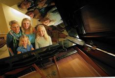 a group of people standing next to each other in front of a piano