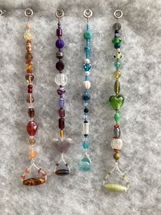 five different colored beads are lined up on a white surface and one is hanging from a hook