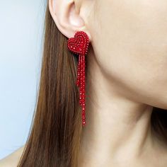 a woman wearing red beaded earrings with long tassels on her ears and neck