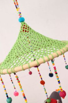 a green crocheted mobile with beads hanging from it