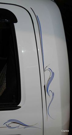 the back end of a white truck with blue swirls on it's side