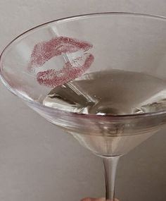 someone holding up a martini glass with lipstick drawn on it