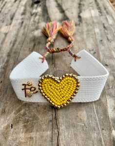 Our Vibrant Miyuki Heart Bracelet: Available in Yellow, Black, Fuchsia, and Gold. Each heart is surrounded by gold beads and filled with colorful Miyuki beads. It's adjustable for the perfect fit and adorned with golden 'FE' letters, symbolizing 'Faith' in Spanish. This Bright, Fun, and Versatile Accessory is Perfect for Any Occasion or as a Thoughtful Gift for a Loved One. - Material: Metal Copper, Miyuki Beads, Woven - Bracelet Length: Approx. 6.69-10.24 inches, Adjustable Jewelry Care: - Our jewelry is delicate. Please roll bracelets on and off gently. Hand it with love and care.  - To keep jewelry looking its best, apply cosmetics and lotions before wearing. - We recommend taking off jewelry before swimming, bathing, exercising, gardening and sleeping. - To keep from tarnishing, store Gold Festival Bracelets With Letter Beads, Gold Friendship Bracelets With Heart Beads For Beach, Adjustable Beaded Heart Friendship Bracelets, Festival Adjustable Beaded Bracelet With Heart Beads, Adjustable Friendship Bracelets With Heart Beads, Adjustable Friendship Bracelets With Heart Beads For Festivals, Adjustable Heart Beads Friendship Bracelet For Festivals, Beaded Heart Bracelet For Friendship, Gold Beaded Bracelets With Letter Beads For Festival