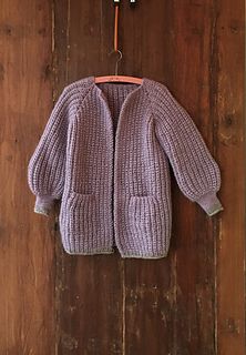 a purple sweater hanging on a wooden wall