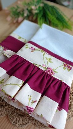 the table is set with two napkins and one has pink flowers on it, along with green leaves