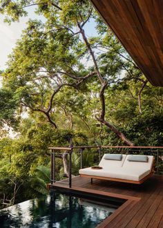 an outdoor deck with chaise lounges and trees in the background, overlooking a pool