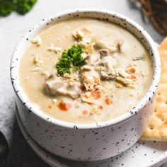 a white bowl filled with soup next to crackers