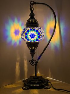 a lamp that is sitting on top of a table next to a wall with colorful lights in the background