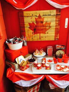 a table topped with cakes and cupcakes next to a canadian flag painting on the wall