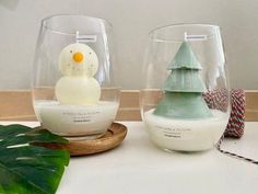 two glass vases sitting on top of a table with a snowman in the middle