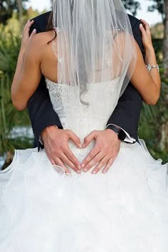 the bride and groom are making a heart shape with their hands