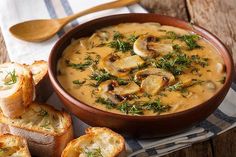 a bowl of mushroom soup with bread on the side