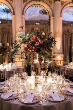 a tall vase filled with lots of flowers sitting on top of a table covered in candles