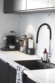 a kitchen sink with a black faucet and white counter top next to it