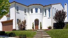 a large white house sitting on top of a lush green field