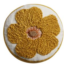 a close up of a yellow flower on a white cloth with orange and brown trim