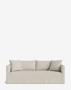 a white couch with three pillows on it's back and one arm facing the camera