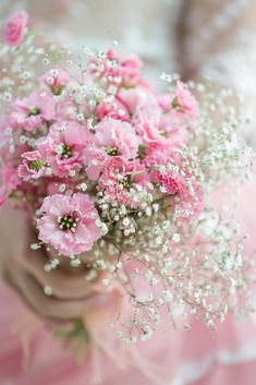 a bouquet of pink and white flowers in someone's hand