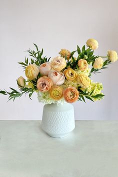 a white vase filled with lots of different colored flowers