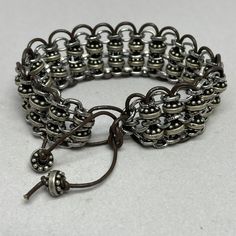 Woven bracelet, silver chain and beads woven with dark brown leather cord.  Is adjustable 7 inches to 9.5 inches.   The bracelet is 3/4 inch wide.  Reminiscent of chain mail.  To see more unique creations, click here: https://KingBlazCreations.etsy.com I take great pride in providing exceptional quality and service!  My top priority is your satisfaction of the design you've ordered.  I want you to love your jewelry as much as I loved creating it.  Please contact me if your expectations are not m Adjustable Metal Jubilee Braided Bracelets, Adjustable Gunmetal Metal Bracelet, Adjustable Gunmetal Metal Bracelets, Brown Metal Beaded Bracelets With Round Beads, Brown Metal Beaded Bracelets As Gift, Brown Metal Beaded Bracelets For Gifts, Adjustable Silver Metal Braided Bracelet, Nickel-free Metal Braided Bracelets, Adjustable Gunmetal Jubilee Bracelet