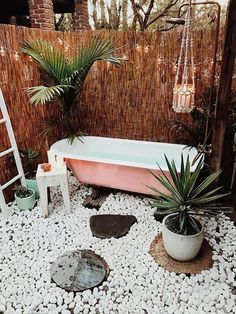 an outdoor bathtub with plants and rocks in the ground, next to a ladder