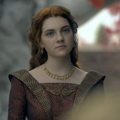 a woman with red hair wearing a gold necklace and dress in a scene from game of thrones