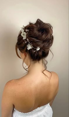 a woman with her back to the camera wearing a white dress and flowers in her hair