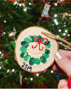 someone is holding up a christmas ornament in front of a tree