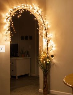 an archway decorated with christmas lights in the corner of a room next to a table